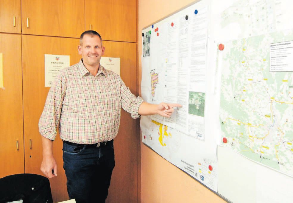 Daniel Jentsch steht vor einer Karte der 18 Gemeinden und zeigt auf ein Projektgebiet