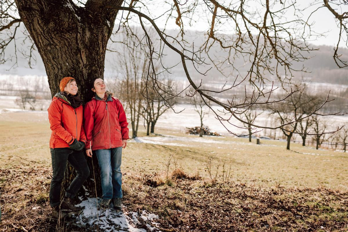 Judit Bartel und Elisa Sichau lehnen an einem Walnussbaum